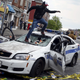 A man jumps on a damaged Baltimore police department vehicle.